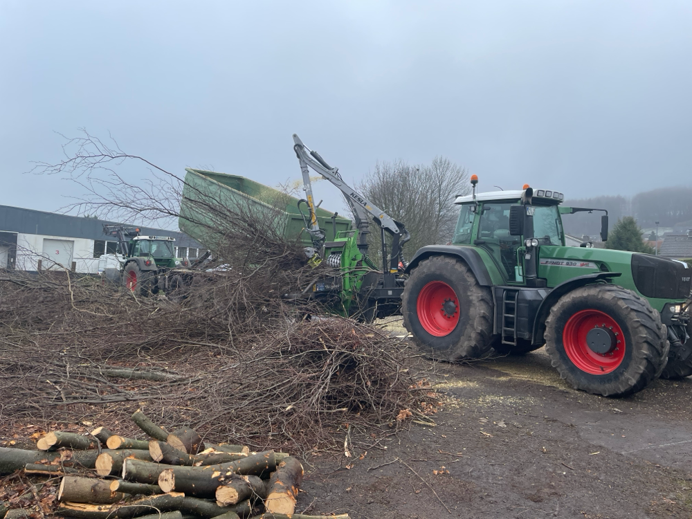 Große Häckselanlage mit zwei Traktoren verarbeitet Äste und Kronenholz nach der Baumfällung auf dem Betriebshof.