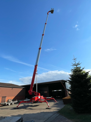 Raupen-Arbeitsbühne auf Hof mit hohem Ausleger